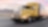 A yellow truck driving down a road at dusk