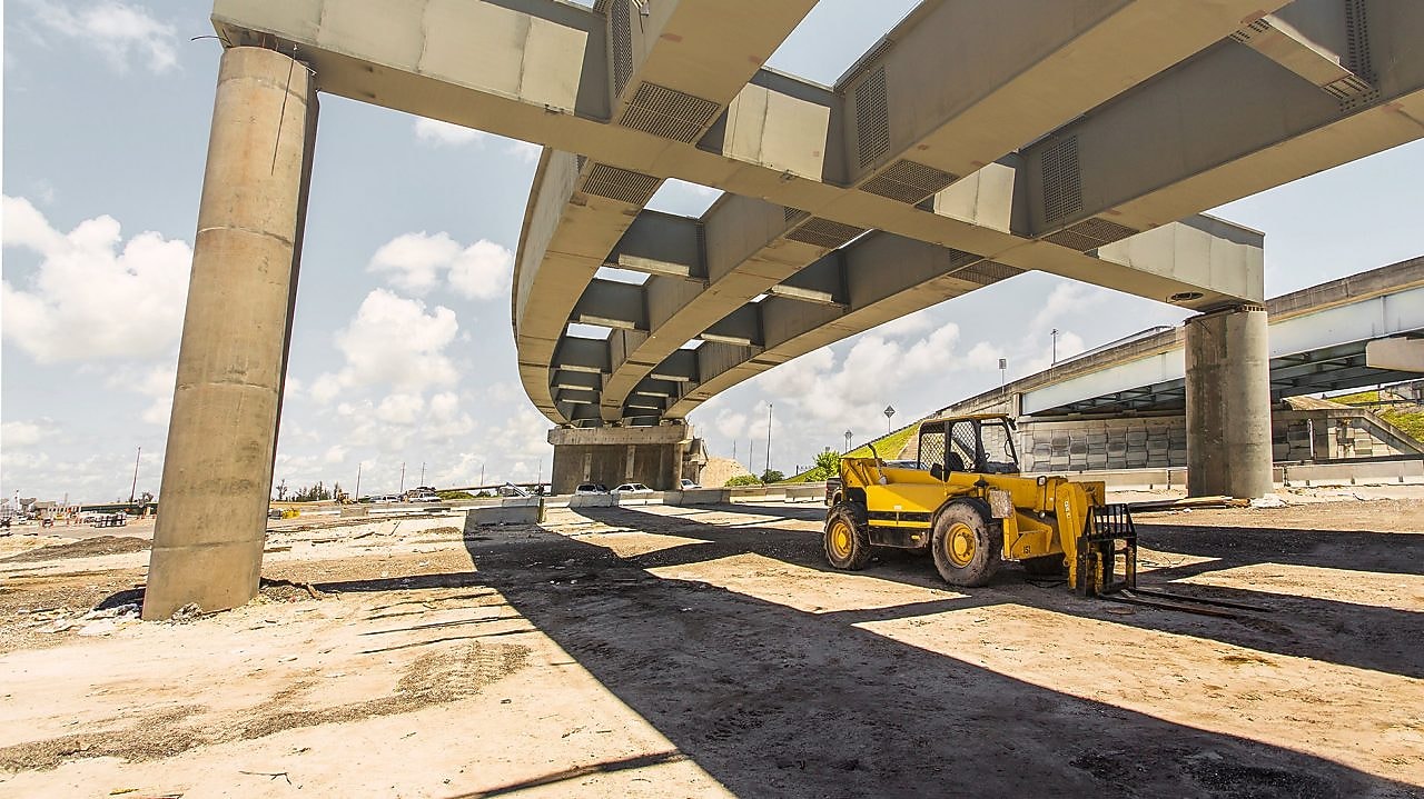 A digger truck under a flyover which is under construction