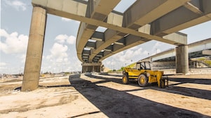 A digger truck under a flyover which is under construction