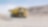 yellow dumper truck driving through gravel