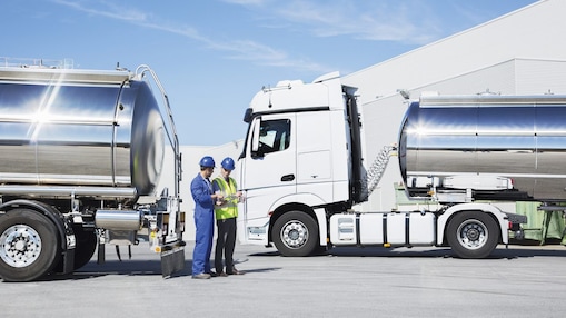 two technicians between two heavy oil trucks
