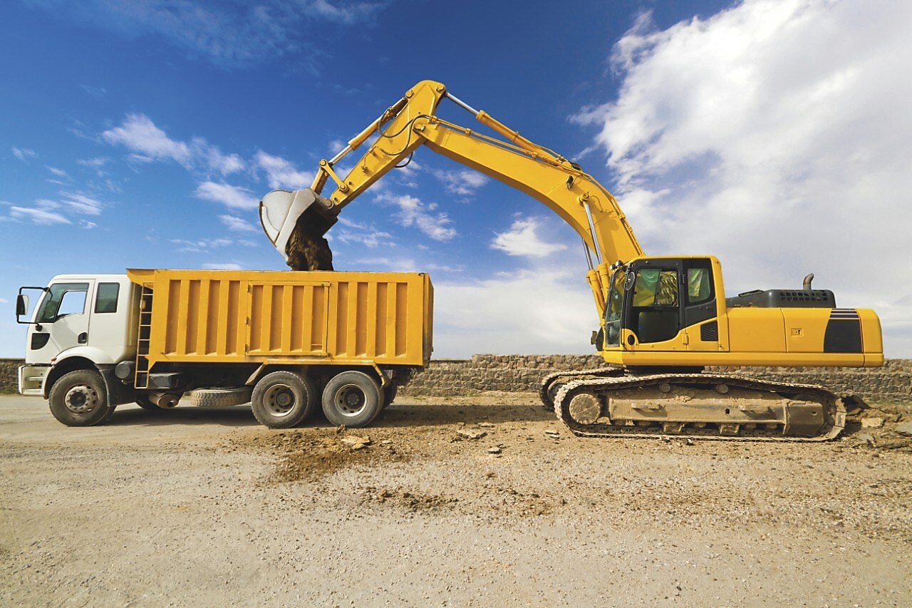 Yellow excavator loading mud into a truck