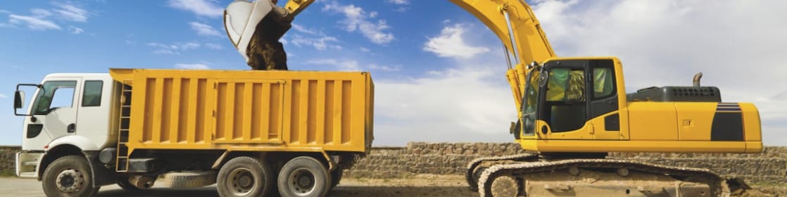 Yellow excavator loading mud into a truck