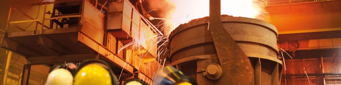 workers watching heavy machinery in a metal processing plant