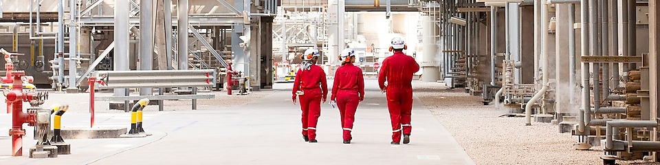 Three engineers walking onsite at a refinery